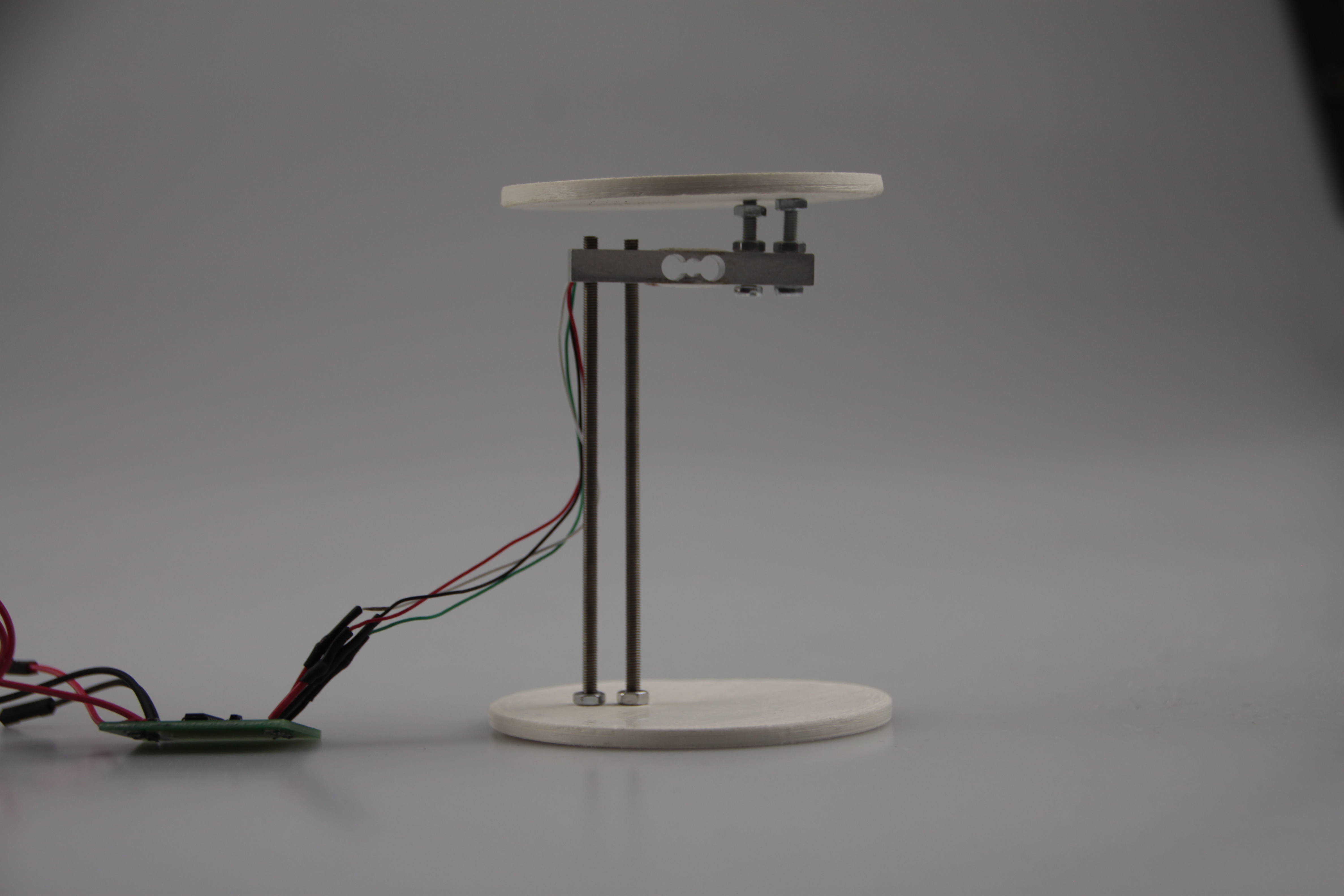Load cell assembly with two 3D-printed discs and threaded rods, isolated on grey